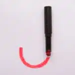 J letter made with makeup lipstick beauty style, black and red tube on white surface