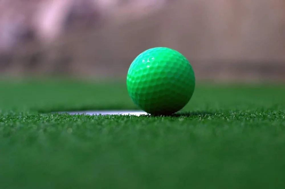 Mini golf, a green golf ball sitting on top of a green field