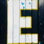 black textured door with withe E hand painted letter., yellow and white wooden door