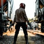 Red Hood, man in brown leather jacket and black pants wearing black helmet