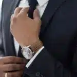 Adjusting the tie, man wearing watch with black suit