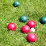 Bocce ball game on grass., red and green balls in green field