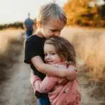 , boy in black t-shirt hugging girl in red and white polka dot dress