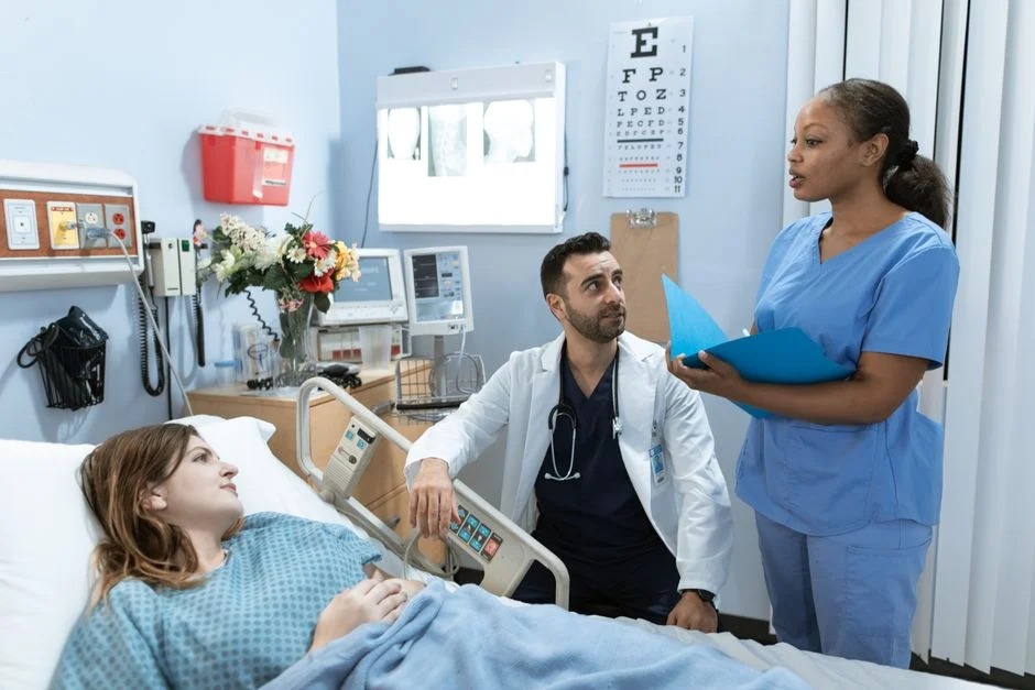 Doctor and nurse consulting with patient in hospital room during care discussion